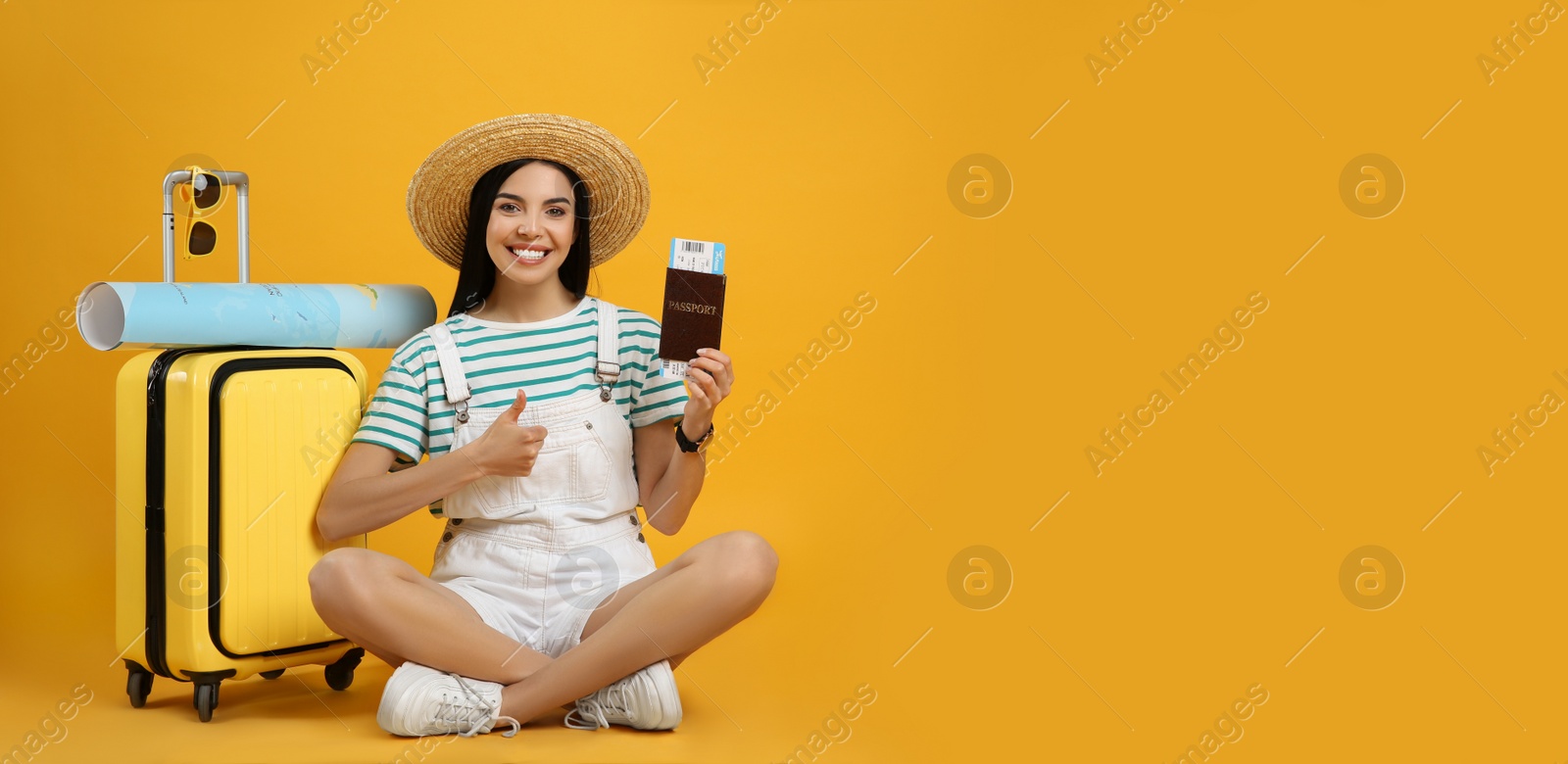 Photo of Happy female tourist with ticket, passport, suitcase and map on yellow background