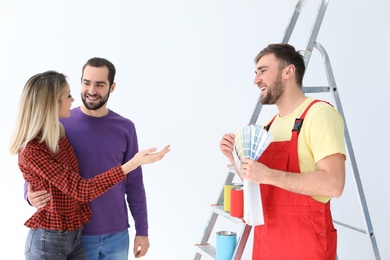 Photo of Male decorator and young couple with color palette on white background