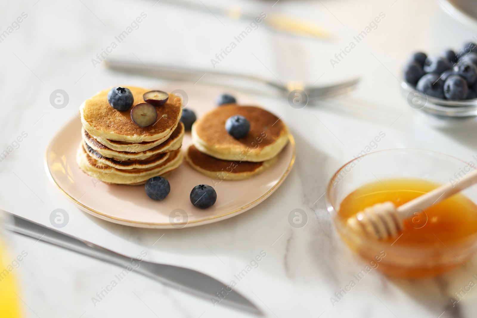 Photo of Tasty breakfast. Fresh pancakes with blueberries on white marble table, selective focus