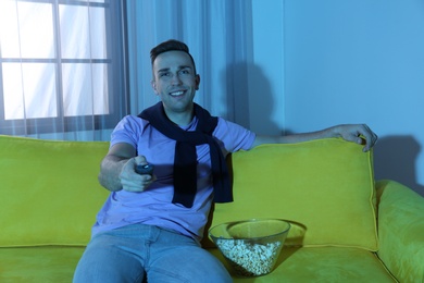 Photo of Handsome young man watching TV on sofa at home