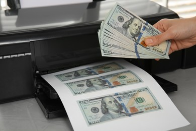 Photo of Counterfeiter printing dollar banknotes at grey table, closeup. Fake money concept
