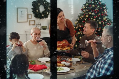 Happy family enjoying festive dinner at home, view through window. Christmas celebration