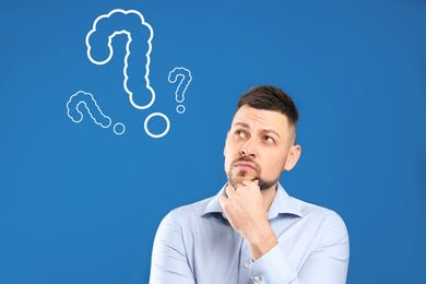 Image of Emotional man with drawings of question marks on blue background