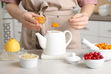 Photo of Woman making immunity boosting drink with turmeric powder at marble table, closeup