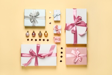 Photo of Beautiful gift boxes, Christmas balls and confetti on beige background, flat lay