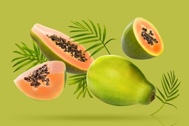 Image of Fresh papaya fruits and leaves falling on bright green background