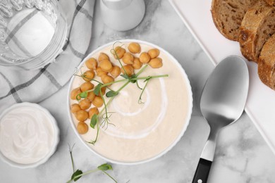 Photo of Flat lay composition of tasty chickpea soup in bowl, sauce and bread served on white marble table
