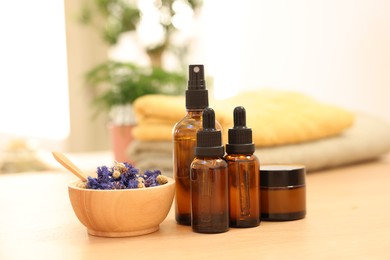 Photo of Dry flowers, bottles of essential oils and jar with cream on wooden table indoors. Spa time