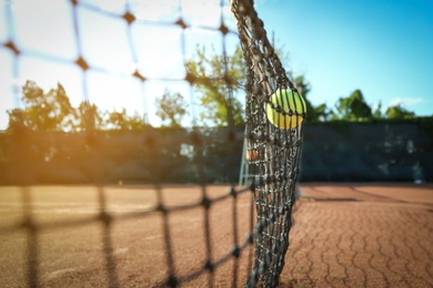 Photo of Bright yellow tennis ball hitting into net on court