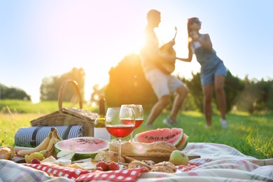 Photo of Happy couple having fun on picnic in park, focus on blanket