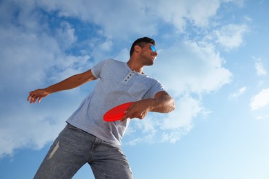 Photo of Happy man throwing flying disk against blue sky on sunny day, low angle view