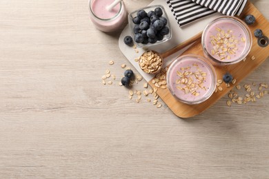 Photo of Glasses of tasty blueberry smoothie with oatmeal on wooden table, flat lay. Space for text