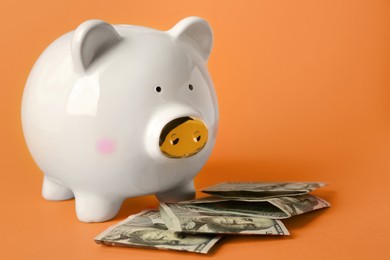 Photo of Ceramic piggy bank and banknotes on orange background. Space for text