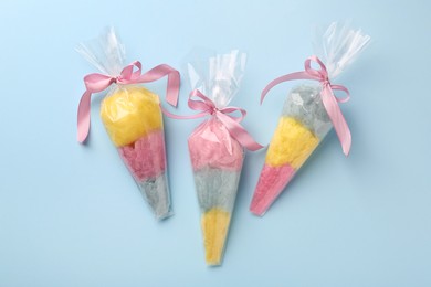 Photo of Packaged sweet cotton candies on light blue background, flat lay
