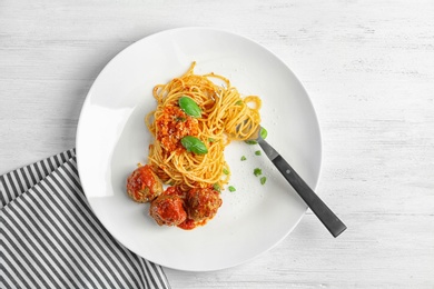 Delicious pasta with meatballs and tomato sauce on wooden background