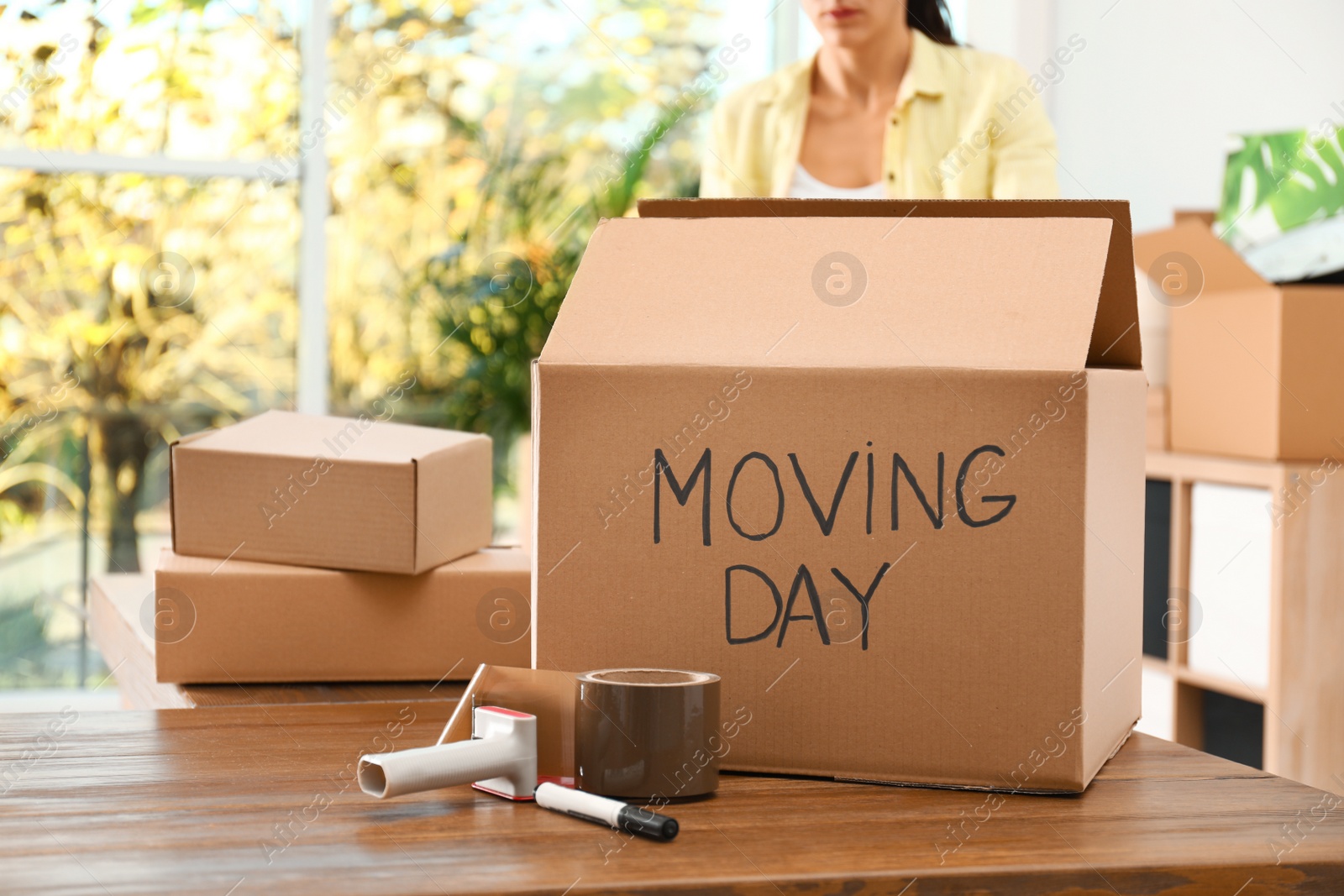 Photo of Cardboard box with words MOVING DAY and packaging items on wooden table