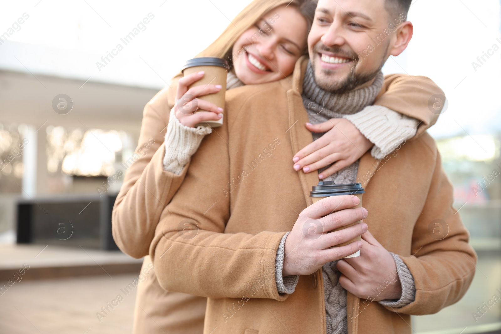 Photo of Lovely couple with cups of coffee on city street in morning