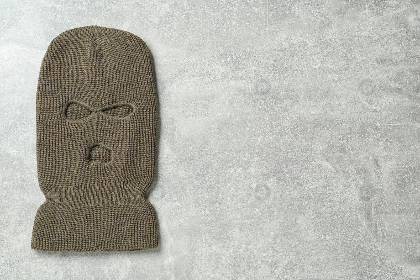 Photo of Beige knitted balaclava on grey table, top view. Space for text