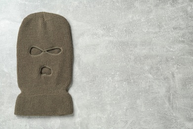 Beige knitted balaclava on grey table, top view. Space for text
