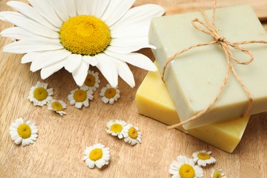 Photo of Composition with chamomile flowers and soap bars on wooden table, closeup