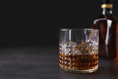 Golden whiskey in glass with ice cubes on table. Space for text