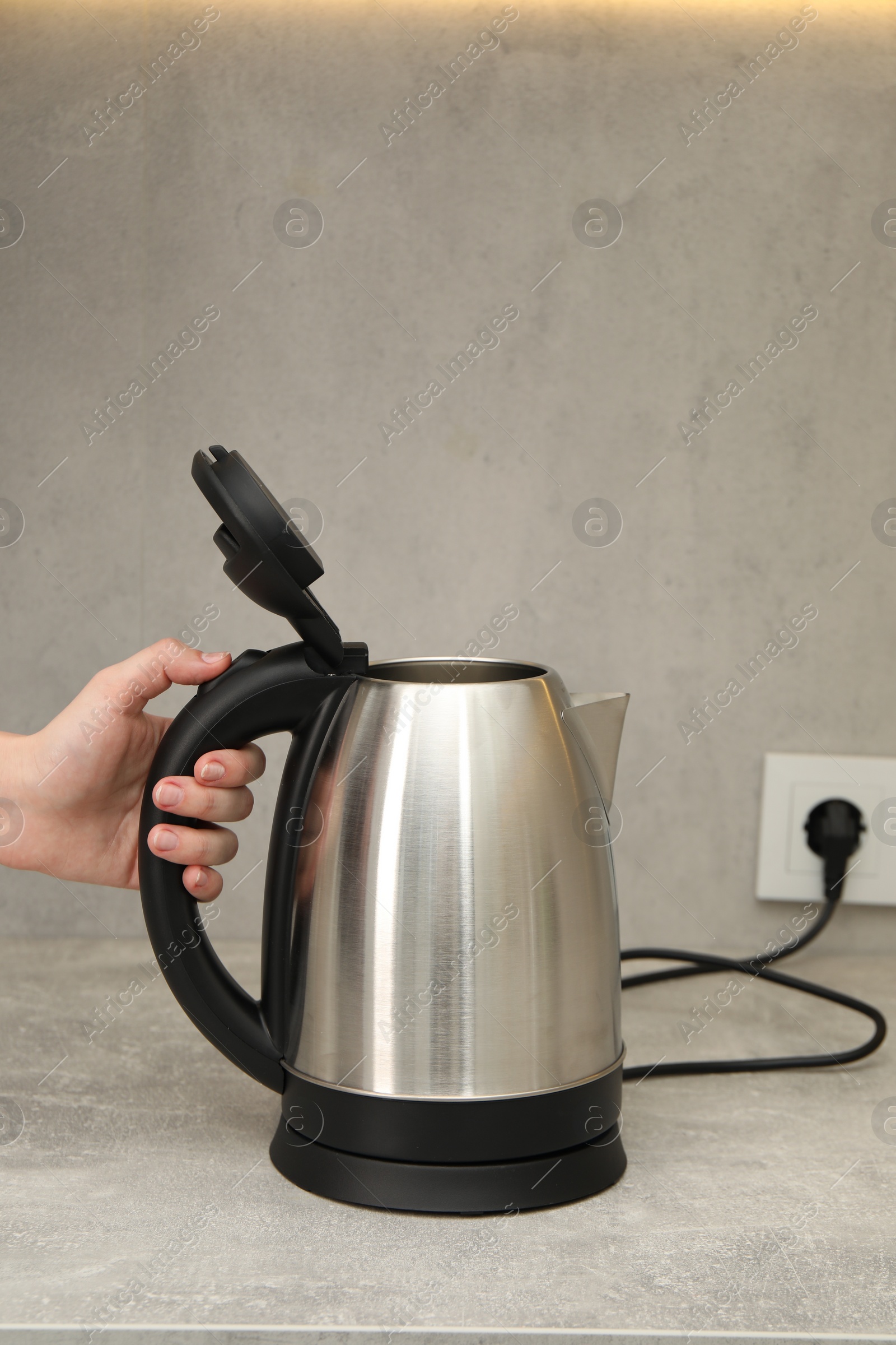 Photo of Woman with electric kettle in kitchen, closeup