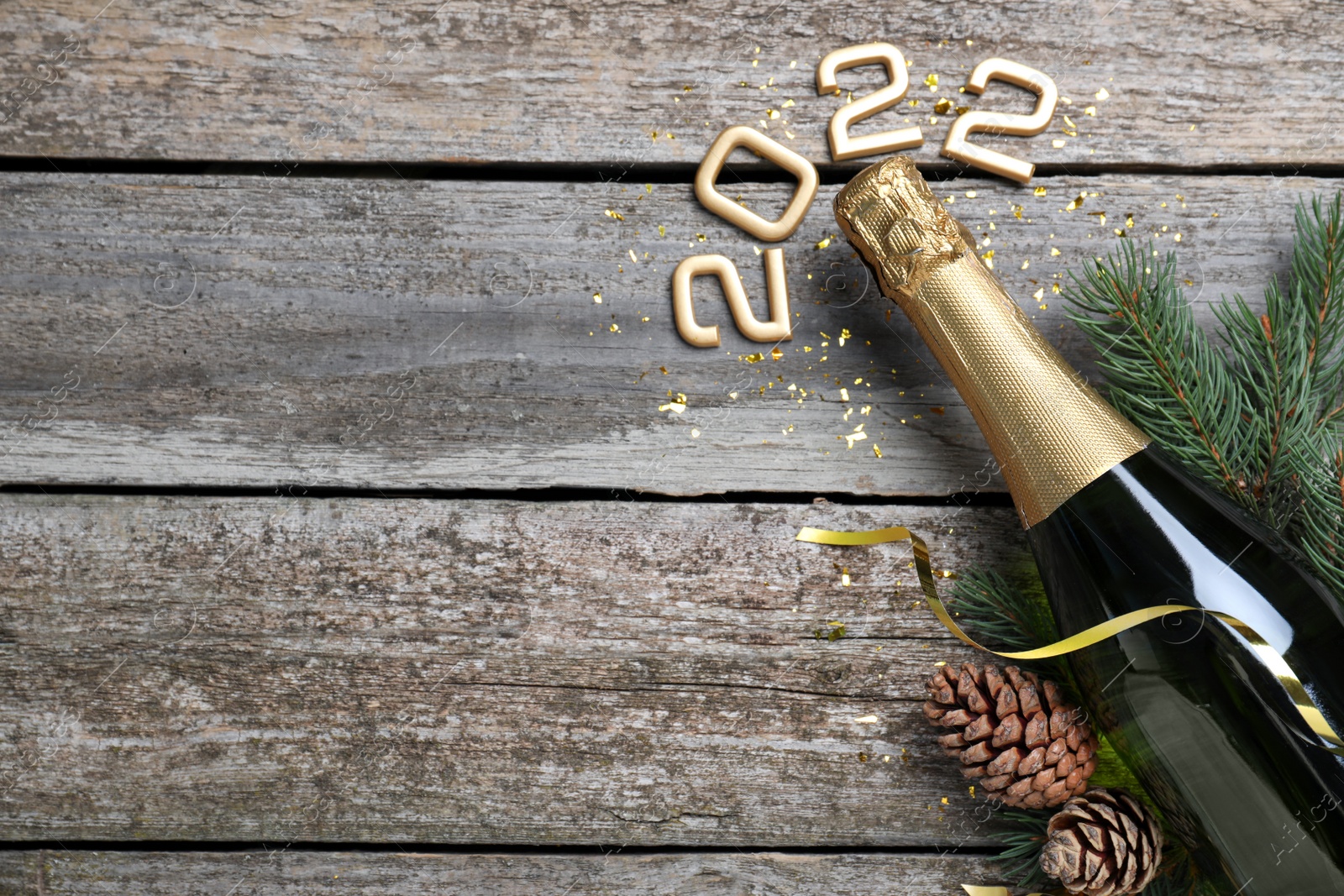 Photo of Happy New Year 2022! Flat lay composition with bottle of sparkling wine on wooden table, space for text
