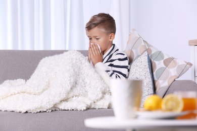 Photo of Ill boy suffering from cough on sofa at home