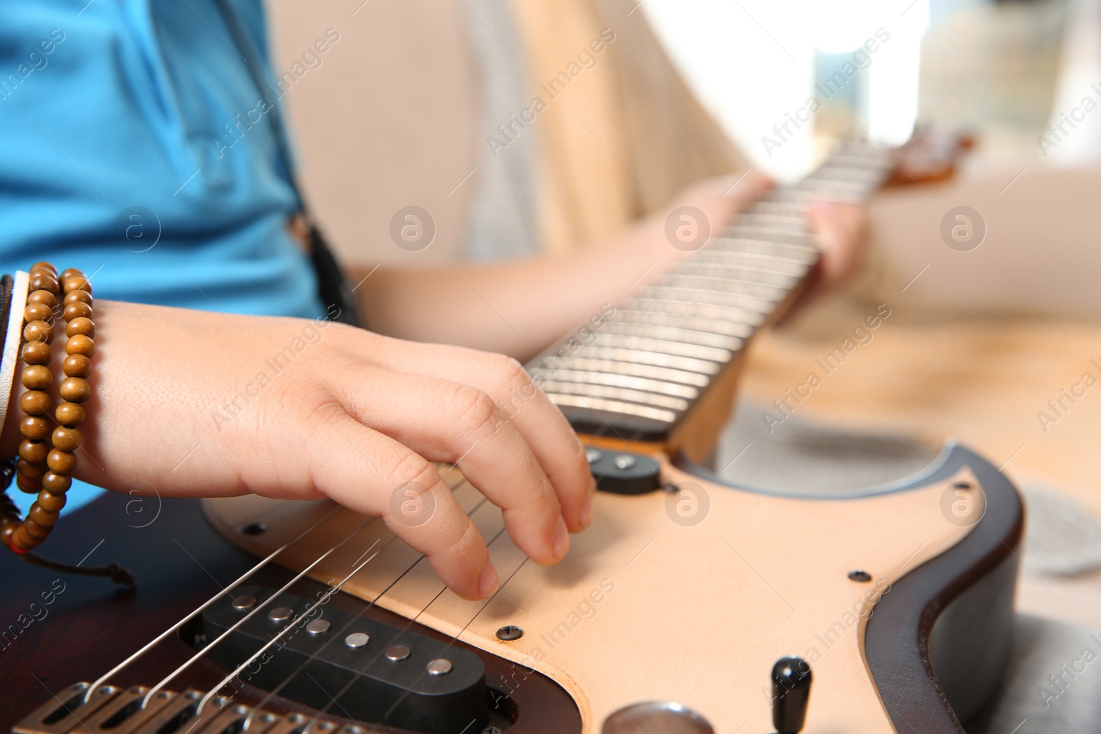 Photo of Little boy playing guitar on sofa, closeup