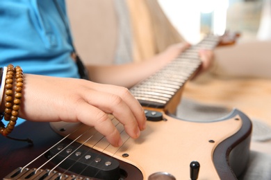 Photo of Little boy playing guitar on sofa, closeup
