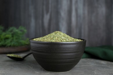 Photo of Bowl with dried dill on grey table