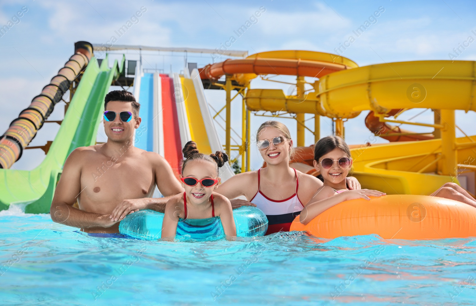 Photo of Happy family with inflatable rings in swimming pool at water park