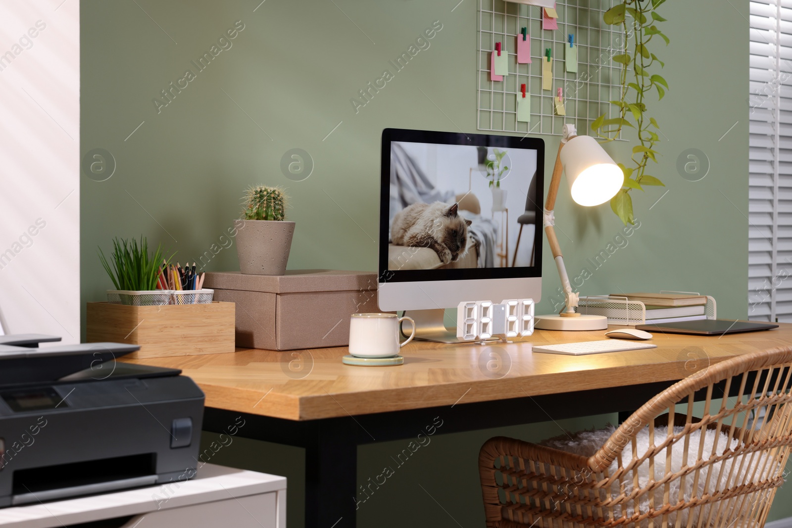 Photo of Stylish workplace with computer, laptop and lamp near olive wall at home