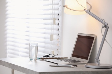 Modern workplace with laptop on grey table in office