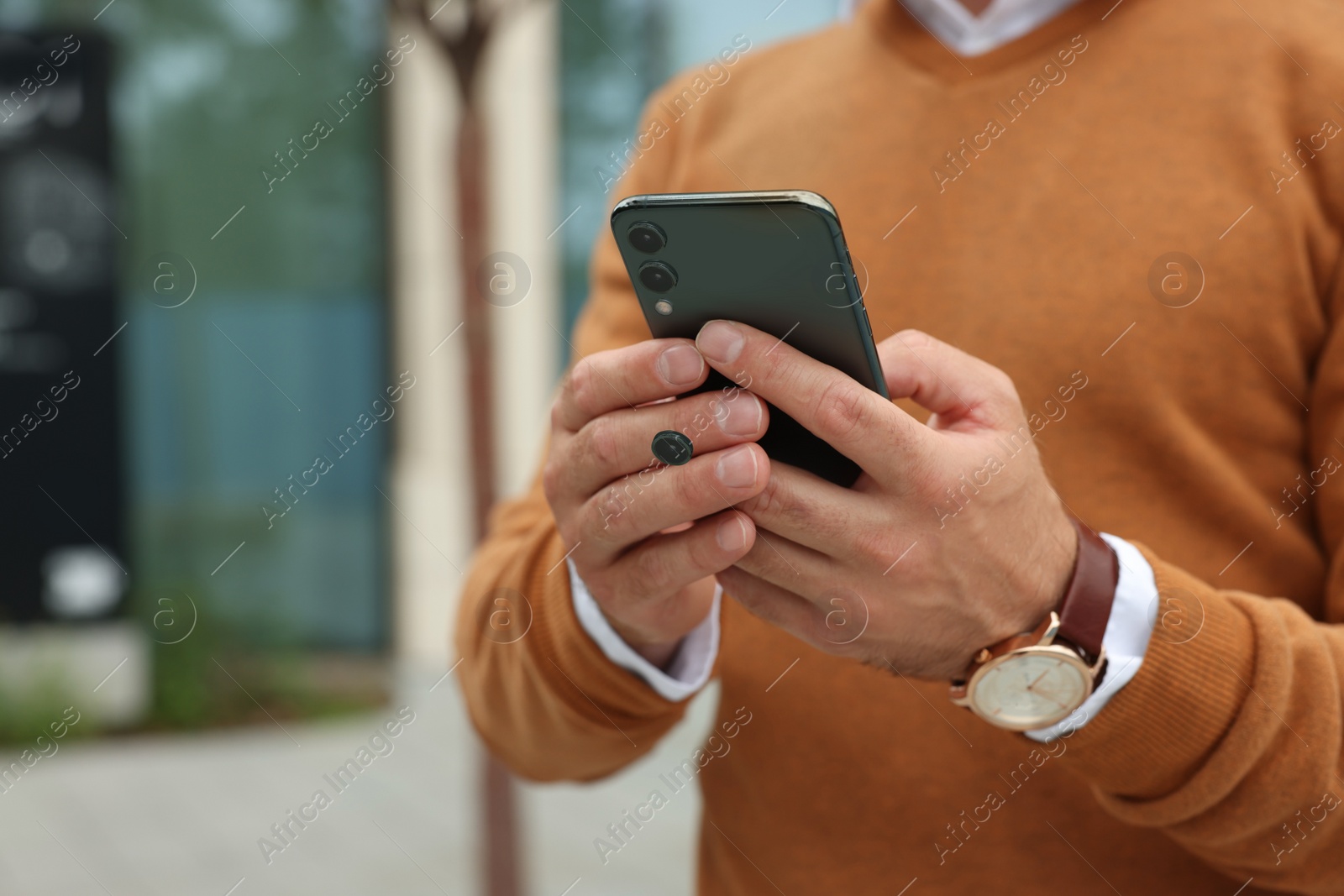 Photo of Man with smartphone on city street, closeup. Space for text
