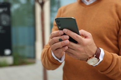 Man with smartphone on city street, closeup. Space for text