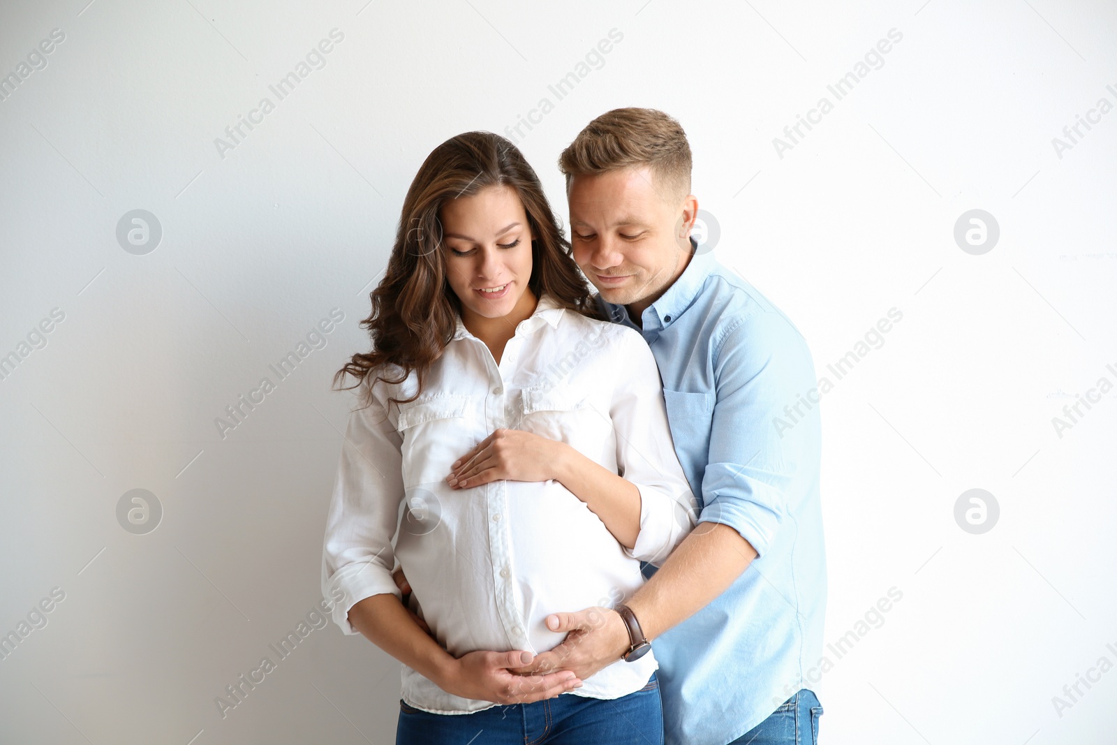 Photo of Pregnant woman with her husband on white background. Happy young family