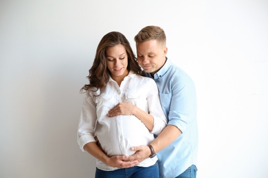 Pregnant woman with her husband on white background. Happy young family