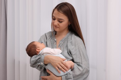 Mother with her cute newborn baby indoors