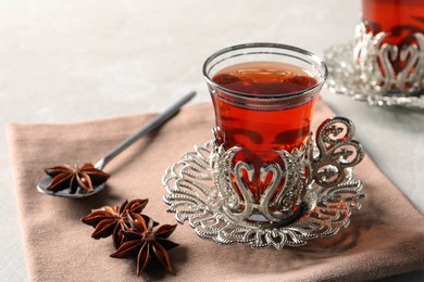 Photo of Glasses of traditional Turkish tea in vintage holders and anise stars on table, closeup