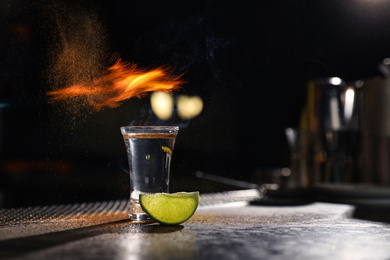 Photo of Mexican Tequila shot with lime slice on bar counter. Space for text