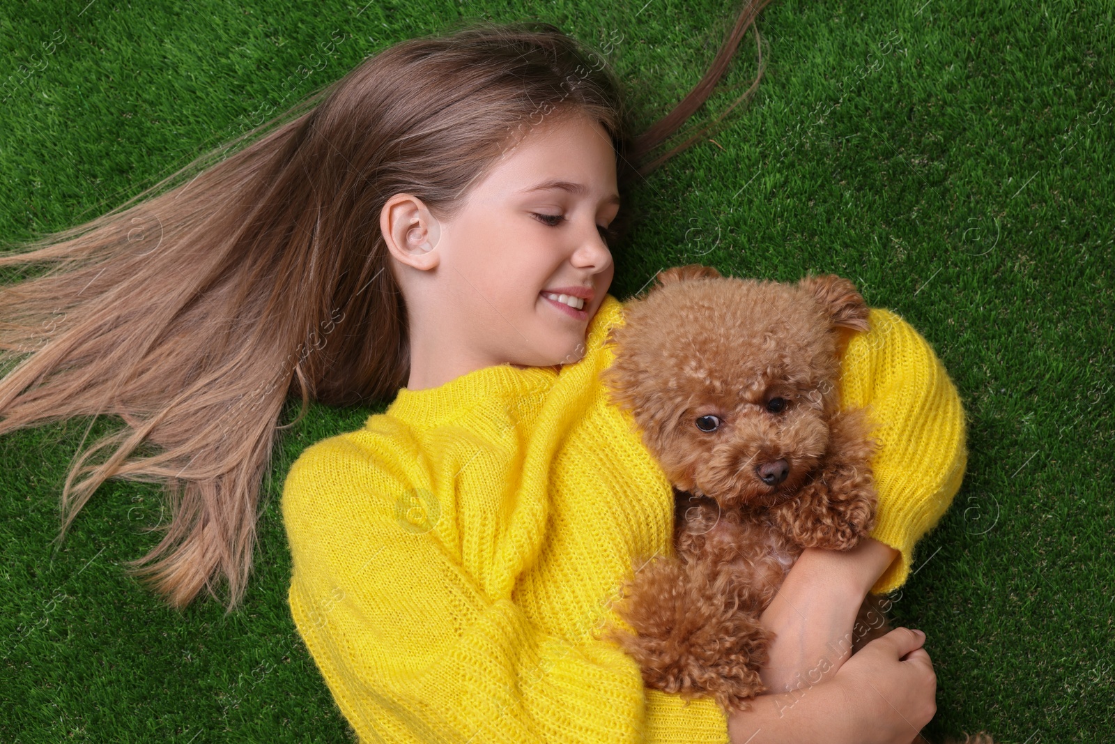 Photo of Little child with cute puppy on green grass, top view. Lovely pet