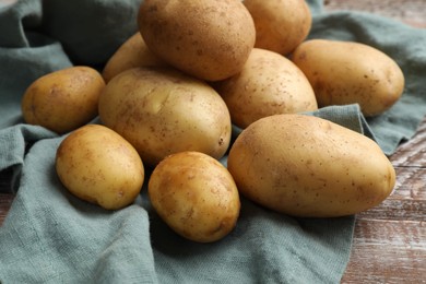 Raw fresh potatoes and napkin on wooden table, closeup