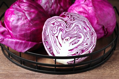 Photo of Closeup view of tasty fresh red cabbages in tray on wooden table