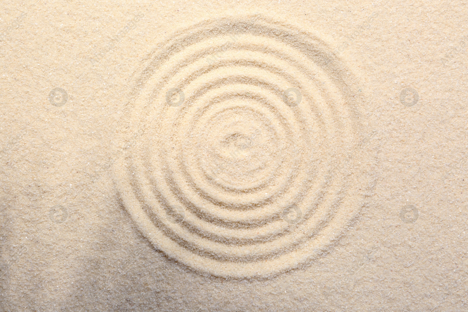 Photo of Zen rock garden. Circle pattern on beige sand, top view