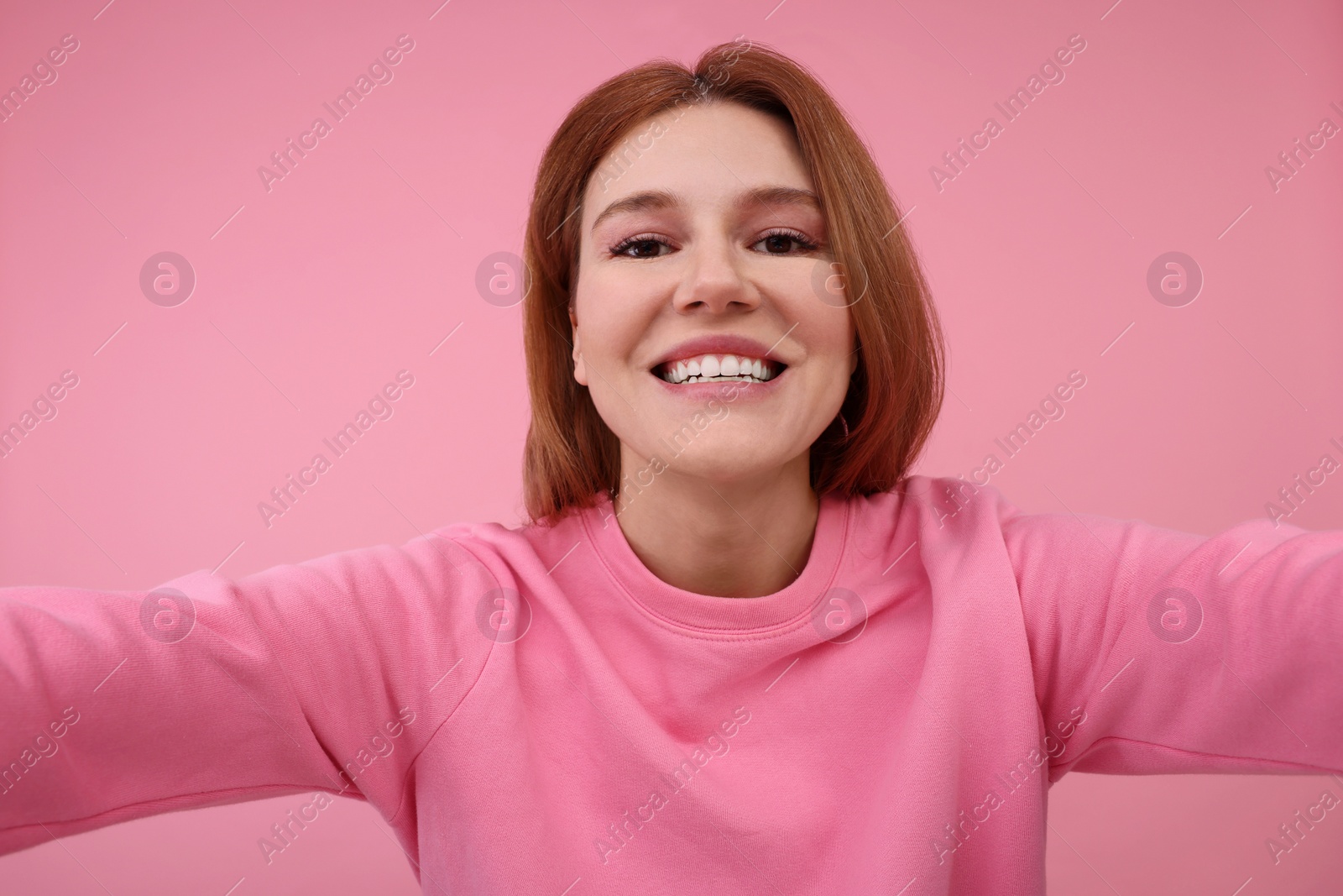 Photo of Beautiful woman taking selfie on pink background