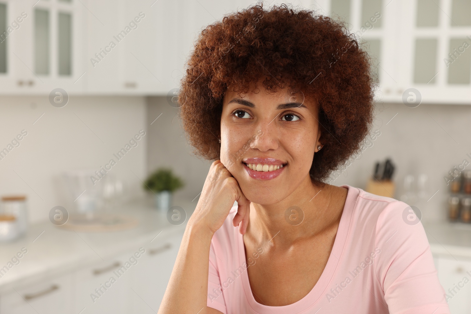 Photo of Portrait of happy young woman in kitchen. Space for text