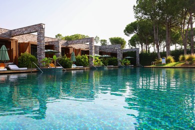 Photo of Swimming pool, exotic plants and sunbeds at luxury resort