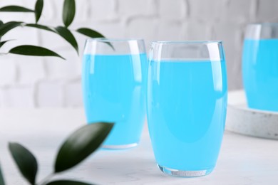 Glasses of delicious blue drink on white table