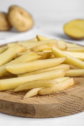 Cut raw potatoes on white table, closeup